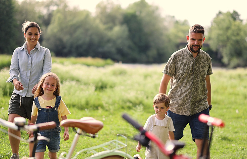 A family walks through a field to their bicycles.